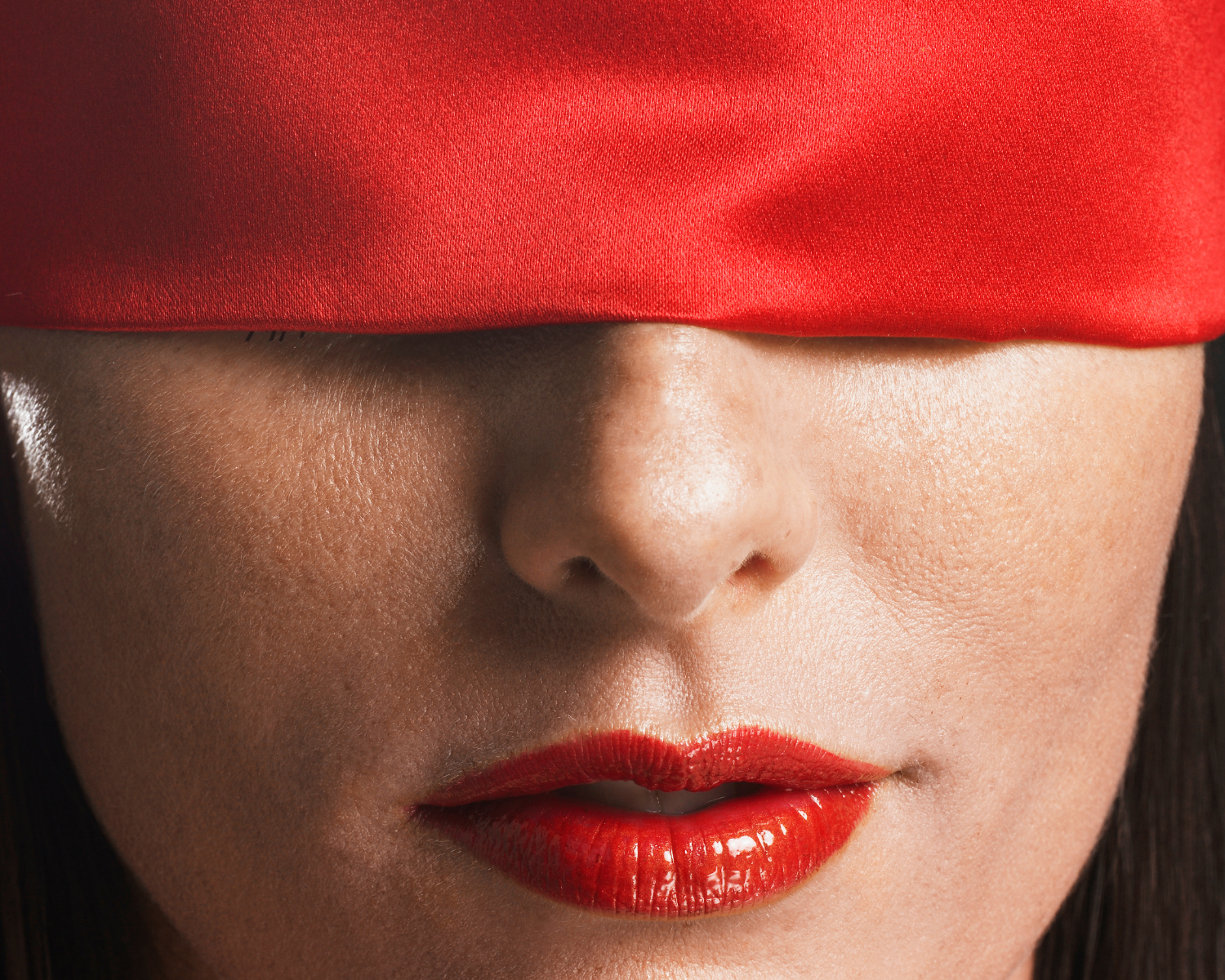 Close-up sensual blindfolded lips in red silk, erotic mystery and desire