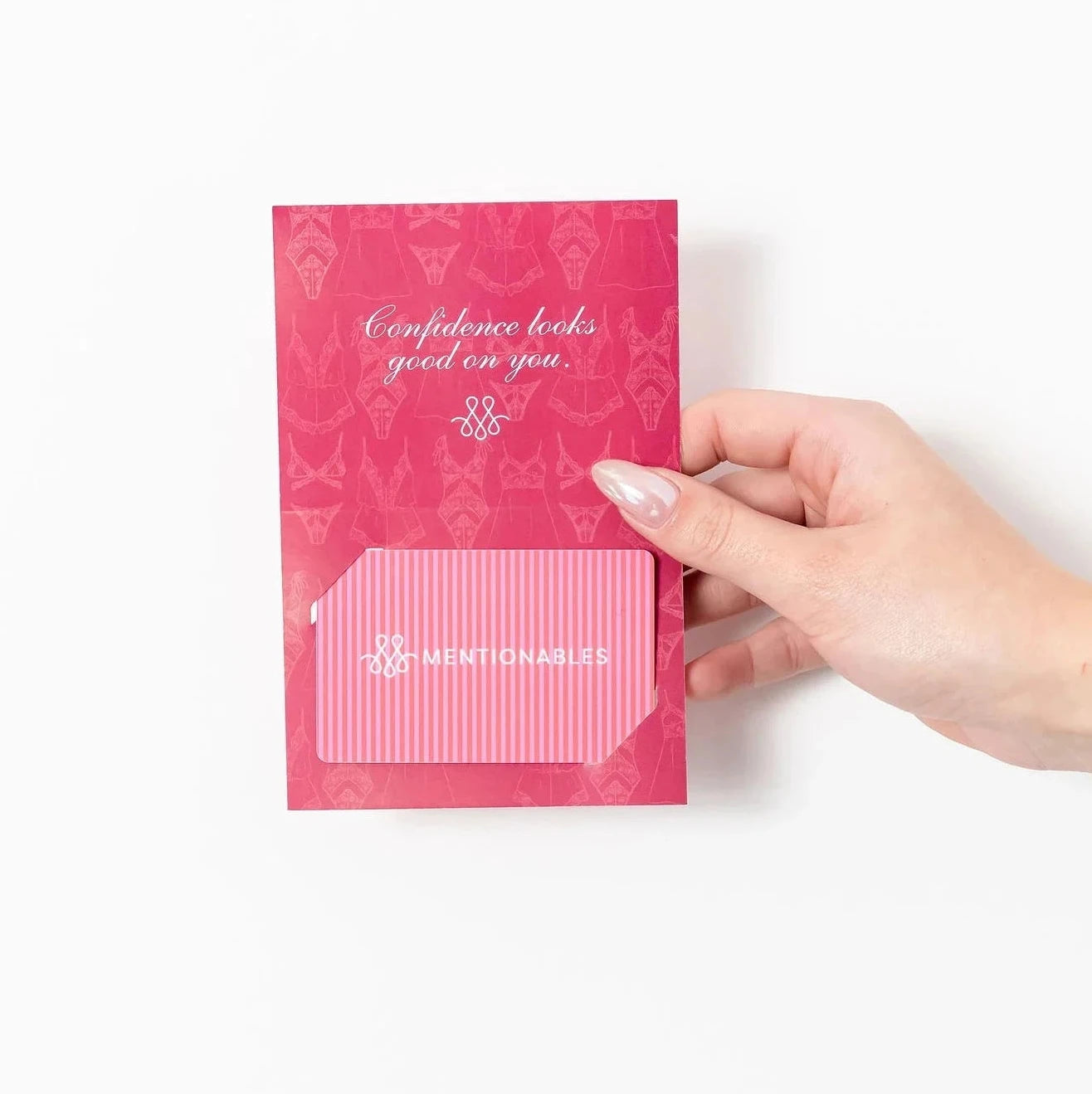 A hand holding a small pink physical gift card with a matching envelope against a plain white background.