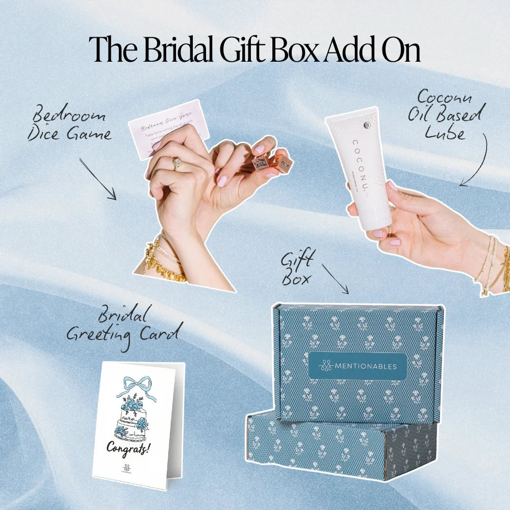 Bridal gift box add-on set featuring a blue patterned gift box, a white coconut oil based lube tube, a dice game card, and a congratulatory card, labeled 'The Bridal Gift Box Add On' on a light blue fabric background.